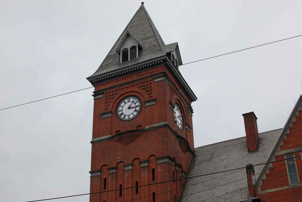 A red brick clock tower rises over Carbondale Town Hall in Lackawanna County, Pennsylvania, with an overcast sky in the background.