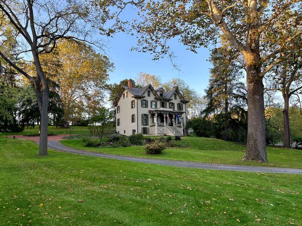 The historic Centre Furnace Mansion in Centre County, Pennsylvania, surrounded by lush green lawns and tall trees, showcasing its 19th-century architecture.