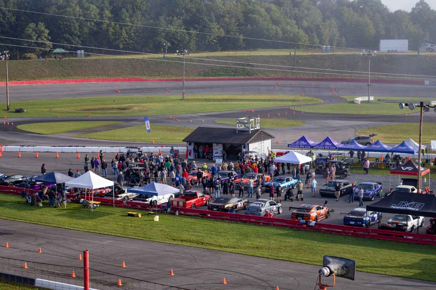 A bustling racetrack event in Clearfield County, featuring classic cars, vendor tents, and a crowd gathered under clear morning skies.