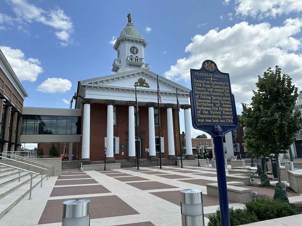 Historic courthouse in Franklin County featuring white columns and a clock tower, with a historical marker in front.