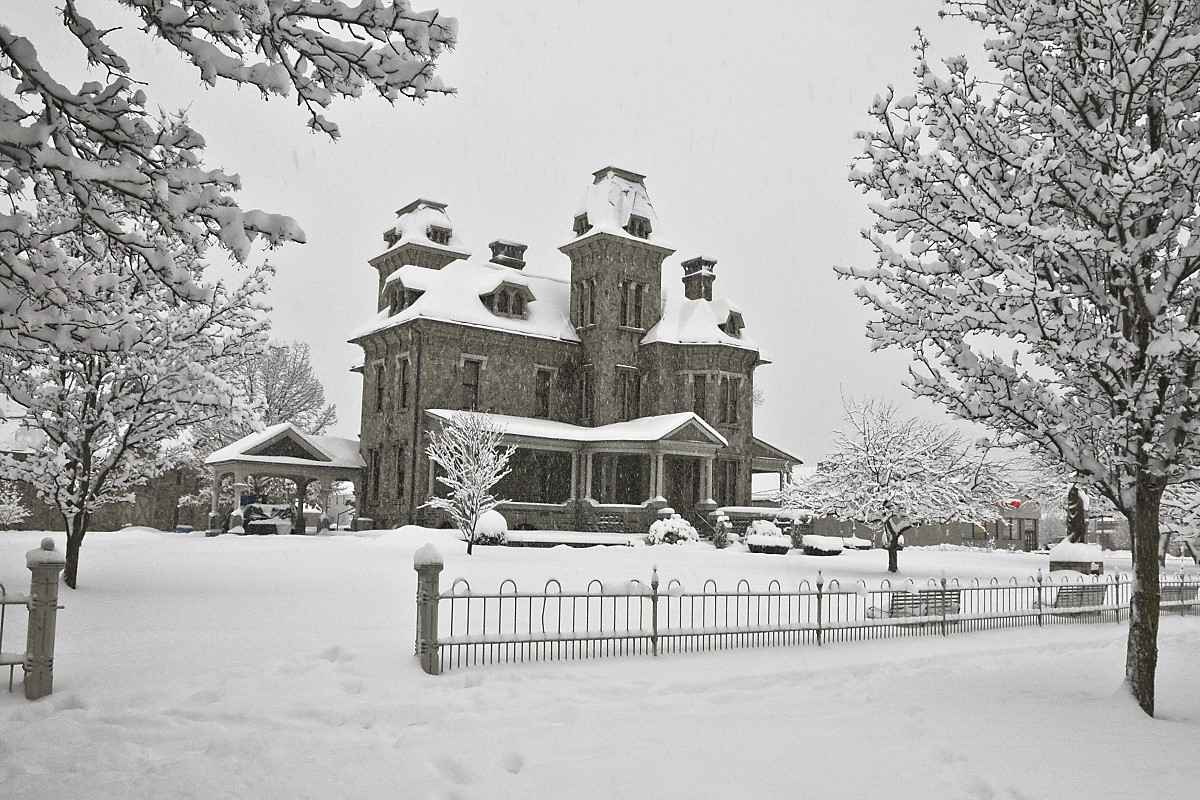 The Jackson Mansion in Columbia County, covered in snow, with its grand stone architecture surrounded by frosted trees, creating a picturesque winter scene.