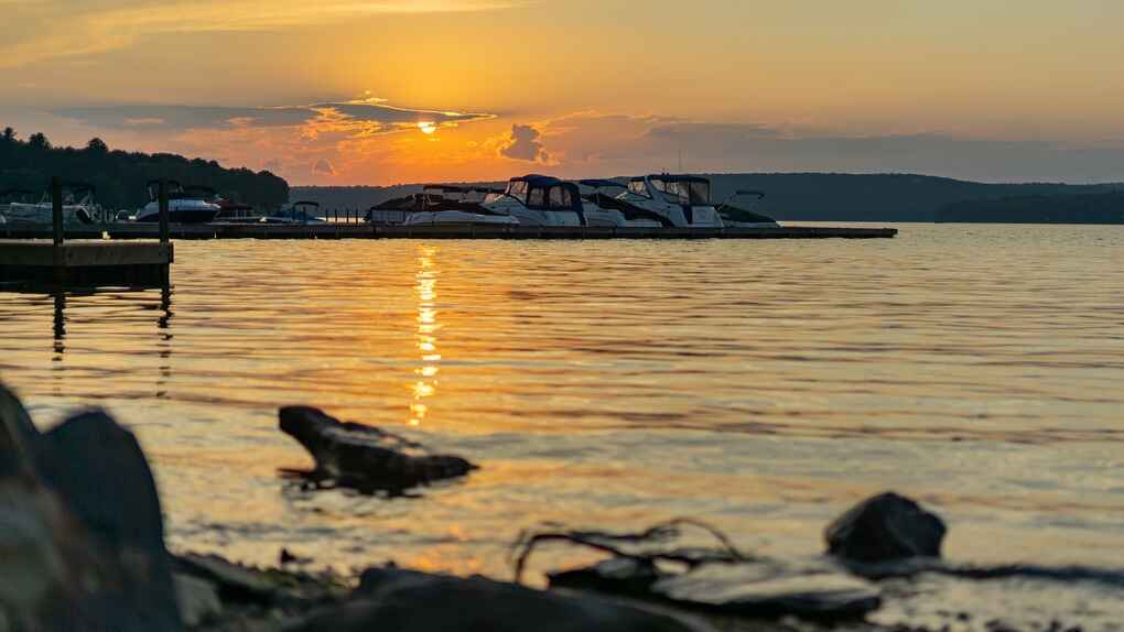 A scenic sunset over Lake Wallenpaupack in Wayne County with boats docked along the water and golden reflections on the rippling surface.