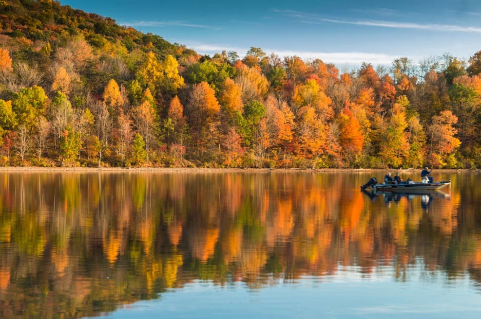 A tranquil lake reflects the brilliant reds, oranges, and yellows of autumn foliage in Rocky Gap State Park, Maryland.