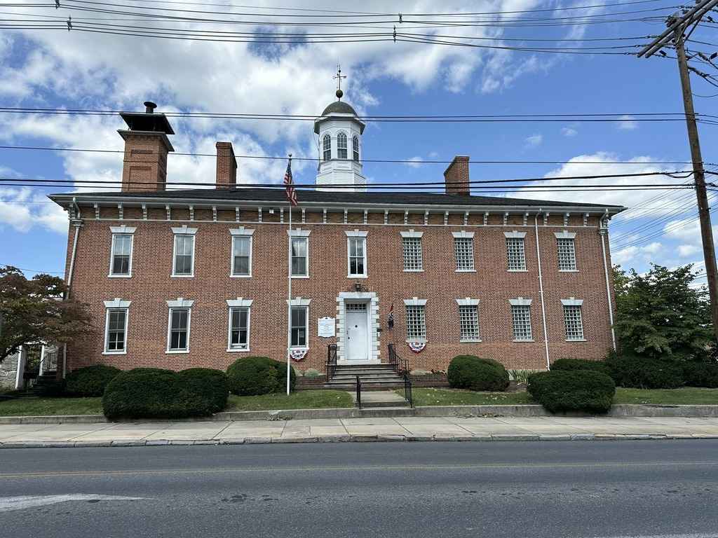 Front view of The Old Jail, a historic red brick building with white-framed windows and an American flag in Franklin County.