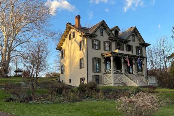 A close-up view of the Centre Furnace Mansion in Centre County, featuring a well-maintained lawn and vibrant fall colors.