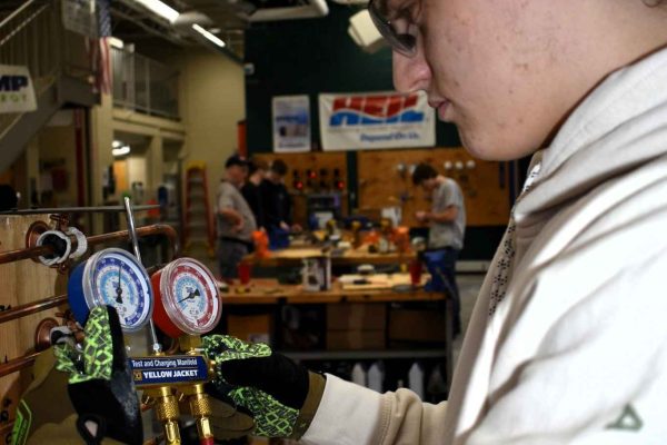 A student in Clearfield County adjusting a pressure gauge during a hands-on technical training session in an industrial workshop.