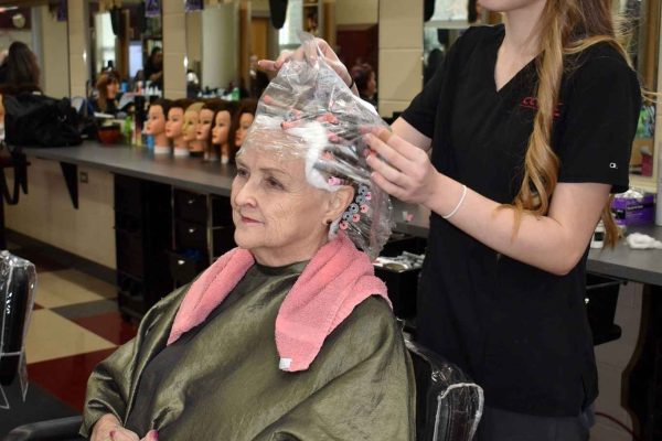 A cosmetology student in Clearfield County carefully wrapping a client’s hair in a salon classroom, showcasing hands-on training.