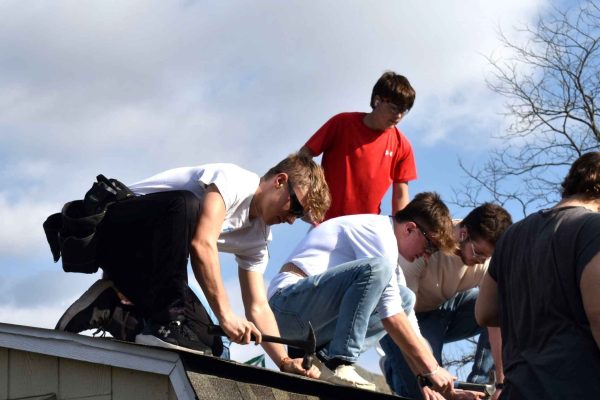 Construction workers on a roof in Clearfield County, collaborating under sunny skies during a community project.