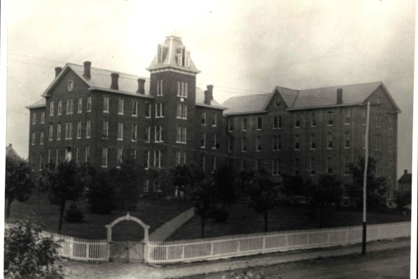 A historic black-and-white photograph of Founders Hall at Juniata College in Huntingdon County, Pennsylvania, showing a large multi-story brick building with a central cupola.