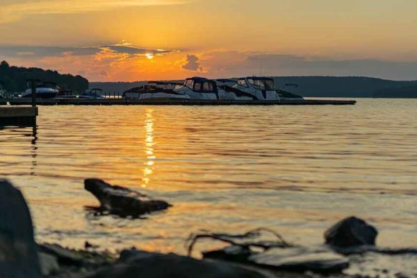 A scenic sunset over Lake Wallenpaupack in Wayne County with boats docked along the water and golden reflections on the rippling surface.