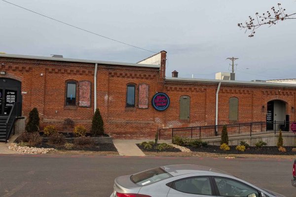 Exterior of River District Golf & Social in Danville, Virginia, housed in a renovated brick industrial building with arched windows and signage.